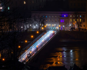 Illuminated street by buildings in city at night