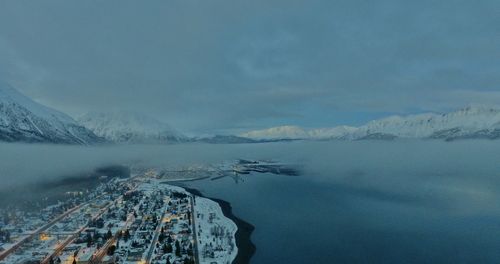 Aerial view of lake by snowcapped mountains against sky