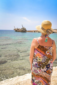 Midsection of woman standing at beach against sky