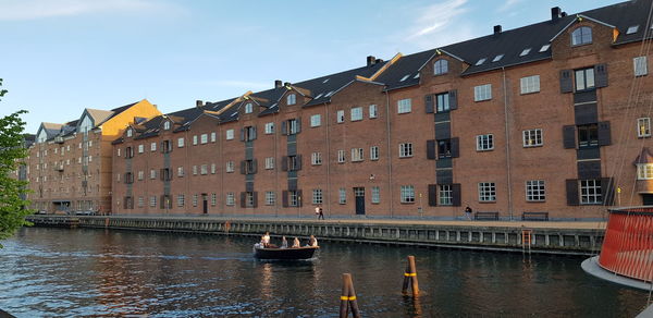 Buildings by canal against sky in city