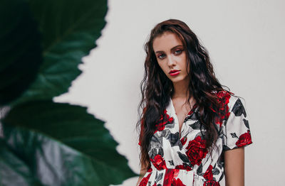 Portrait of a beautiful young woman standing against wall