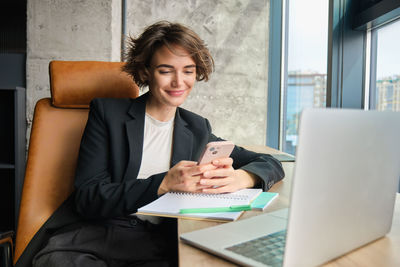 Businesswoman using laptop while sitting on sofa at office