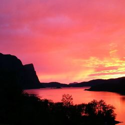 Scenic view of lake against dramatic sky during sunset