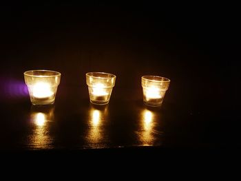 Close-up of illuminated tea light candles against black background