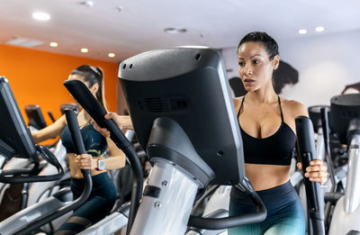 Two women working out in gym using an elliptical trainer