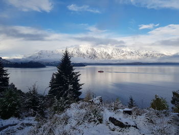 Scenic view of frozen lake by snowcapped mountains against sky