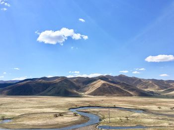 Scenic view of land and mountains against blue sky