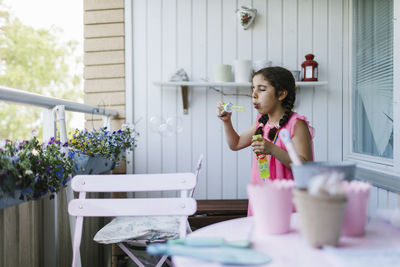 Girl on balcony blowing bubbles