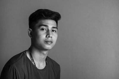 Portrait of young man standing against black background