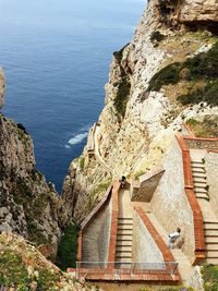 High angle view of stairs on rocky mountains by sea