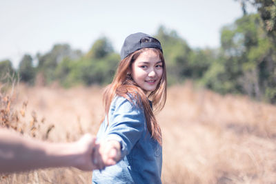 Cropped image of boyfriend holding smiling girlfriend hand on land