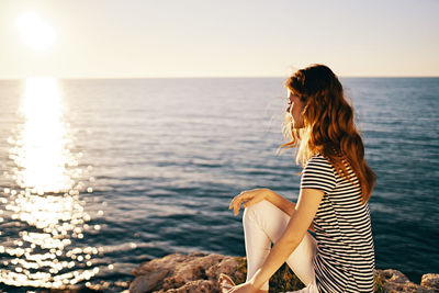 Woman looking at sea against sky during sunset