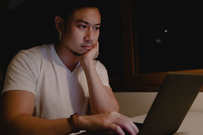 Portrait of young man using mobile phone at home