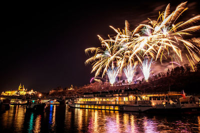 Firework display over river against sky at night