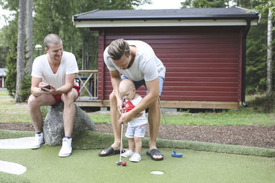 Man and baby boy playing mini golf