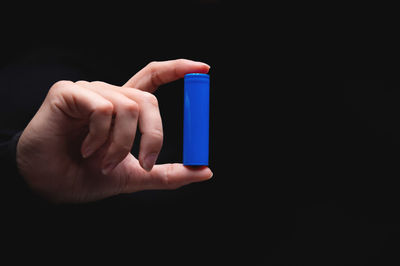 Cropped hand of person holding toy blocks against black background