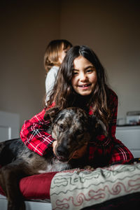 Smiling girl in red pajama holds her grey dog