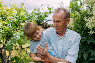 A little girl hugs her grandfather on a walk in the summer outdoors.