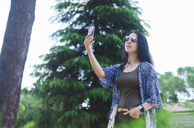 Young happy business woman relaxing in city, park. using phone. selfie. technology. summer vacation
