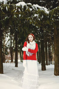 Redhead beautiful woman in red sweater and white gloves walking in the frozen winter forest.