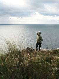 Rear view of woman walking on field against sky