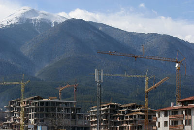 Construction site by mountains against sky