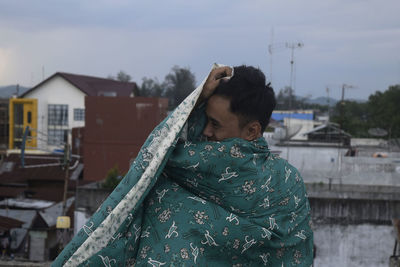 Man with sheet standing against buildings