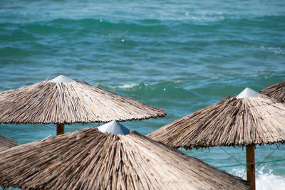 Deck chairs on beach by sea against sky