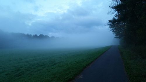 Road amidst field against sky