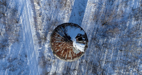 Aerial view of house and bare trees on snow covered land