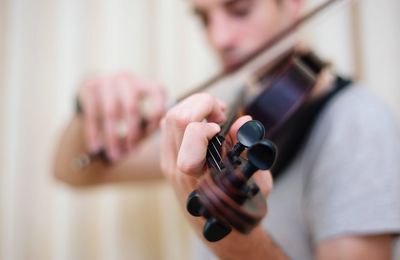 Close-up of young man playing violin at home