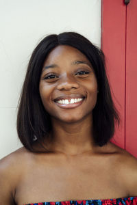 Happy young woman in front of wall