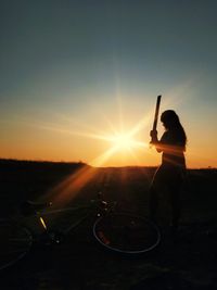 Silhouette woman standing on street against sky during sunset