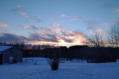 Scenic view of snow covered field against sky at sunset