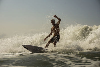 Man surfing in sea against sky