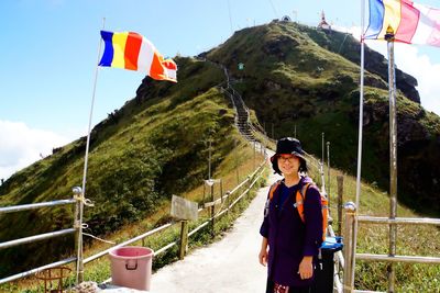 Portrait of woman standing on footpath leading towards mountain