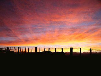 Silhouette fence against sky during sunset