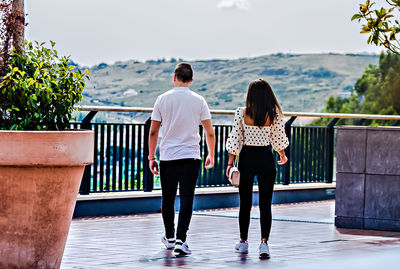 Rear view of friends standing on railing