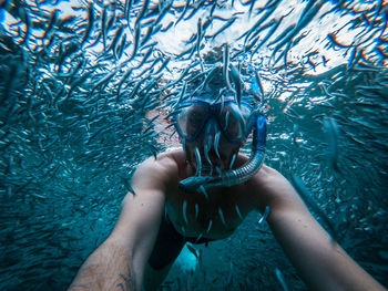 Shirtless man snorkeling amidst fishes in sea