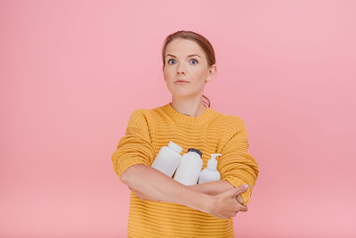 Portrait of woman standing against pink background