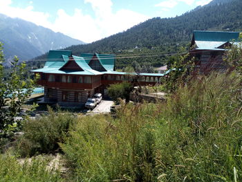 House amidst trees and buildings against sky