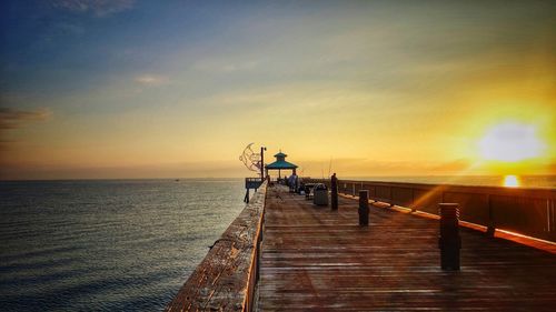 Pier over sea against sky during sunset