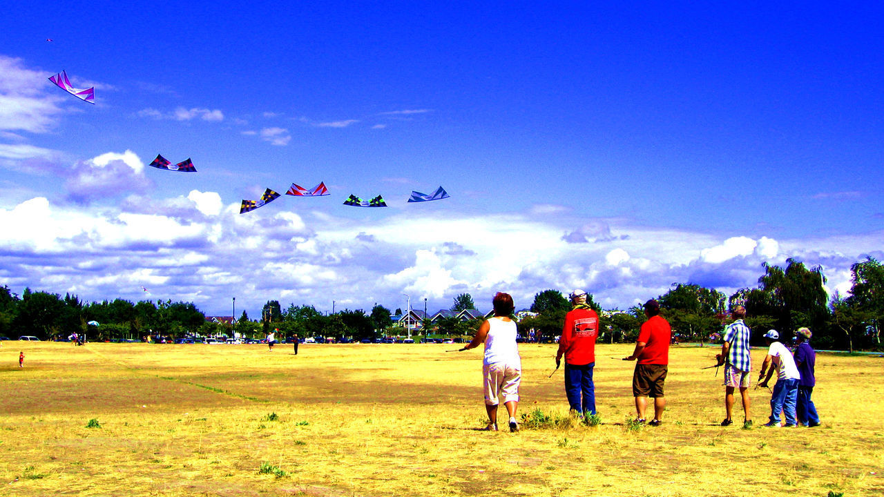 PEOPLE PLAYING FLYING OVER FIELD