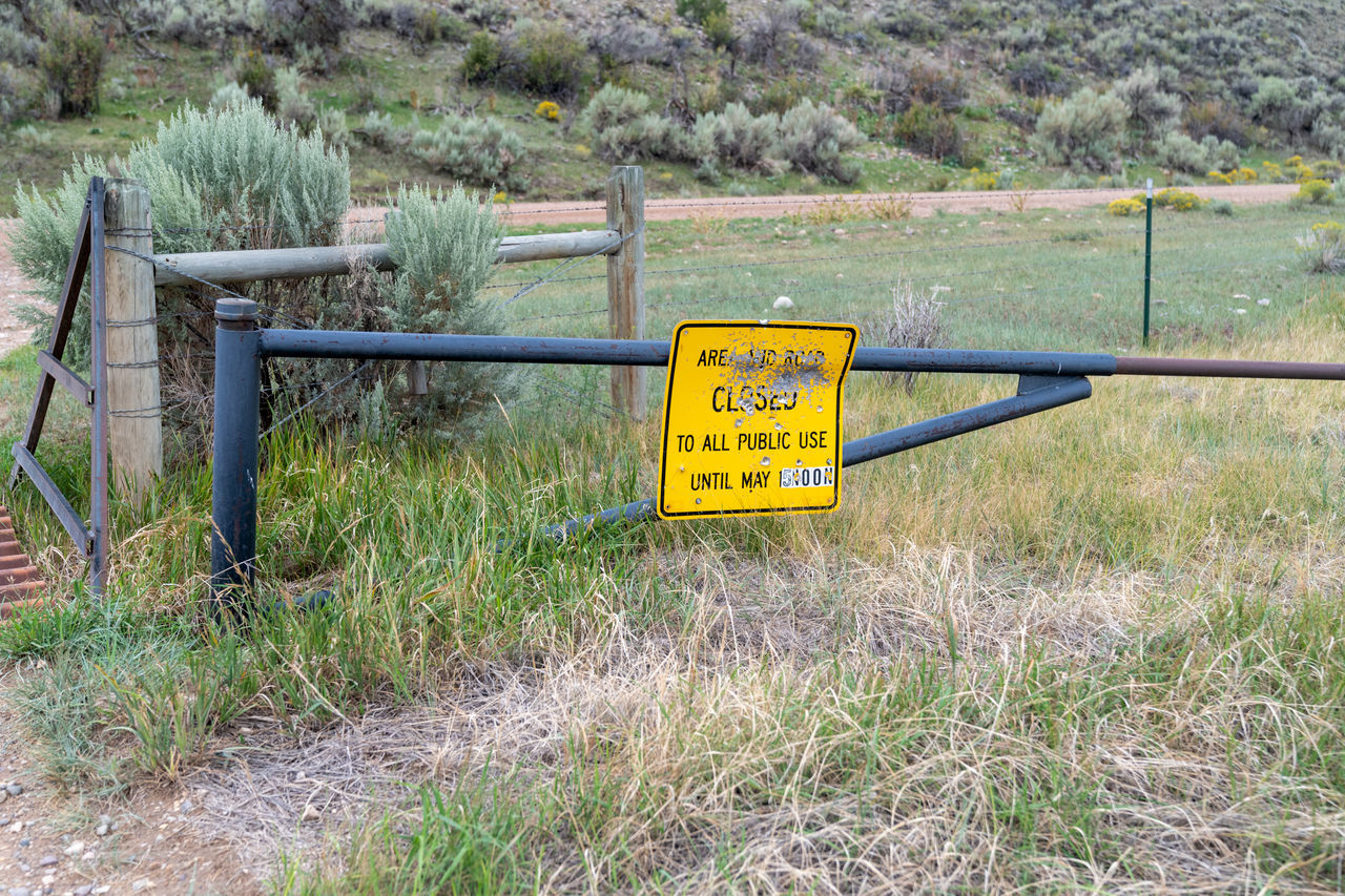 INFORMATION SIGN BY FENCE ON FIELD