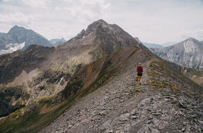 Rear view of man walking on mountain against sky