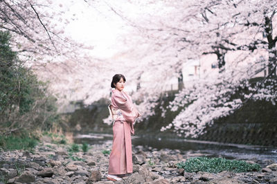 Full length of woman standing by cherry tree