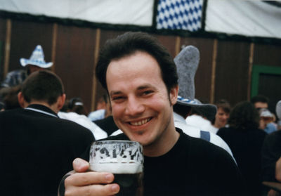 Portrait of man smiling while having beer against people during oktoberfest