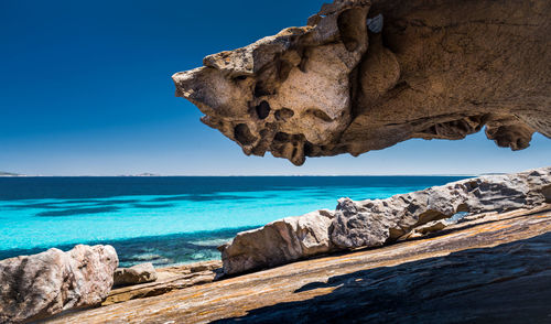 Rock formations in sea against clear blue sky