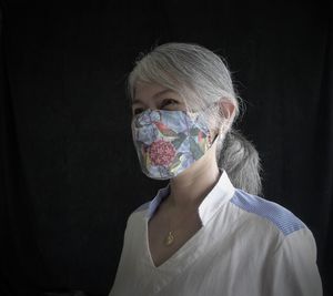 Portrait of woman covering face against black background