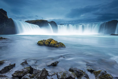 Godafoss waterfall cascading over rocky terrain under cloudy skies in iceland